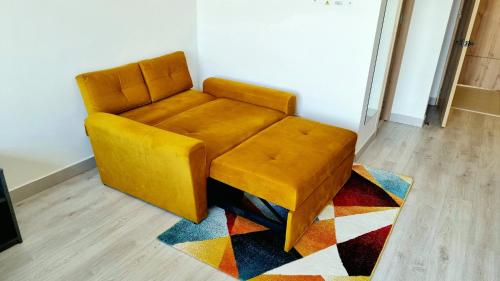 a yellow chair sitting on a rug in a room at Toscana LOFT - Apartasuites in Bogotá
