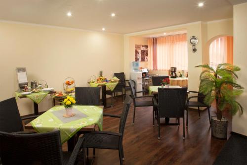 a dining room with tables and chairs and a kitchen at Pension RELAX U Komína in Františkovy Lázně