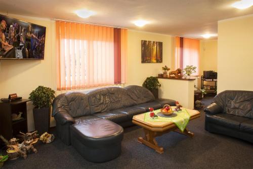 a living room with a leather couch and a table at Pension RELAX U Komína in Františkovy Lázně