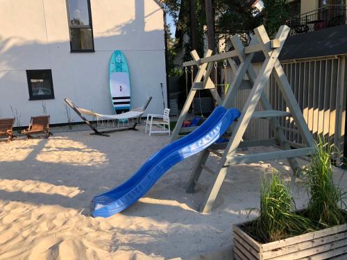 a playground with a blue slide and a surfboard at Playa Pobierowo in Pobierowo