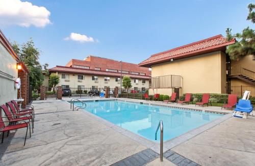 a swimming pool in a courtyard with chairs and a building at Red Roof Inn Santa Ana in Santa Ana