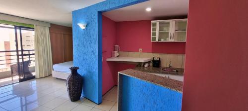 una cocina con paredes rojas y un jarrón en la encimera en Praia Mansa Flat en Fortaleza
