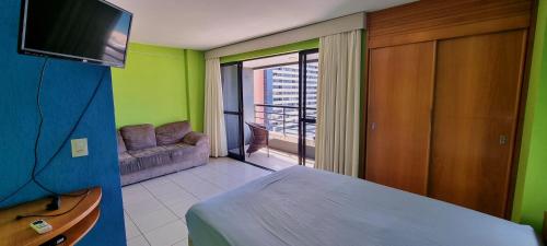 1 dormitorio con cama, sofá y TV en Praia Mansa Flat, en Fortaleza
