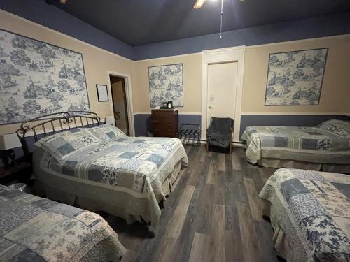 a room with three beds with blue walls and wooden floors at Auberge Presbytere Mont Lac-Vert in Hébertville