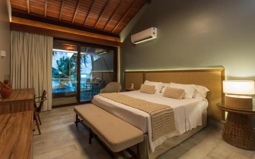 a bedroom with a large bed and a balcony at Serrambi Resort in Porto De Galinhas