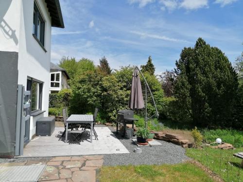 a patio with a table and an umbrella and a grill at Moderne familienfreundliche Wohnung am Waldrand von Prüm mit Terrasse in Prüm