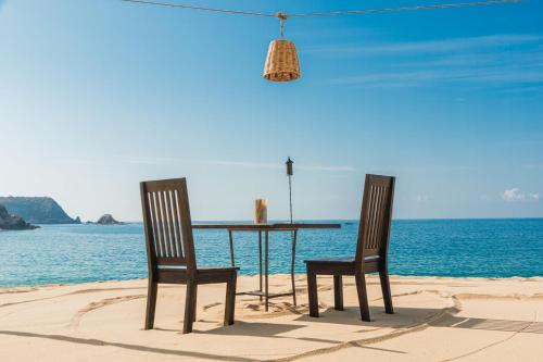 two chairs and a table on the beach at Camino Real Zaashila Huatulco in Santa Cruz Huatulco