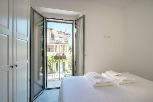 een witte kamer met een bed en een groot raam bij The bell tower apartment - Bellagio center in Bellagio