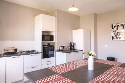 - une cuisine avec des placards blancs et une table fleurie dans l'établissement Trésor de Brou *NEW LOCATION, à Bourg-en-Bresse