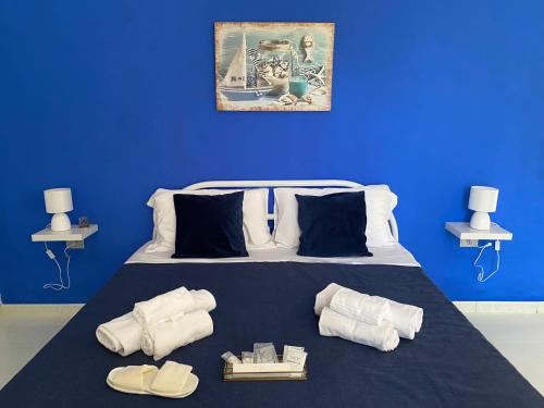 a blue bedroom with a bed with towels and shoes at Il Giardino Di Capo Vaticano B&B and Apartments in Capo Vaticano