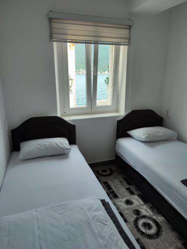 two beds in a room with a window at Apartment Rosić in Perast