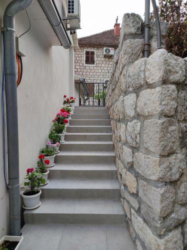 a stone wall with stairs and potted plants at Apartment Rosić in Perast