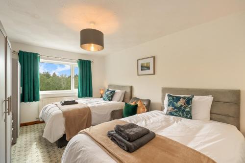 two beds in a room with green curtains at Trefelyn Cottage in Saundersfoot