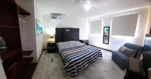 een slaapkamer met een bed en een blauwe stoel bij Villa Quintas Del Mar in Mazatlán