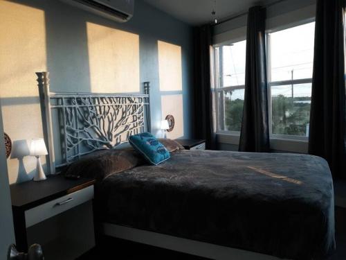 een slaapkamer met een groot bed en 2 ramen bij Las Casitas on Magnolia Beach - Casita A in Port Lavaca