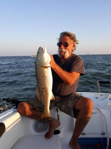 a man sitting on a boat holding a fish at Las Casitas on Magnolia Beach - Casita A in Port Lavaca