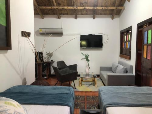 a room with two beds and a couch and a tv at Finca Hotel Brasilia in La Tebaida