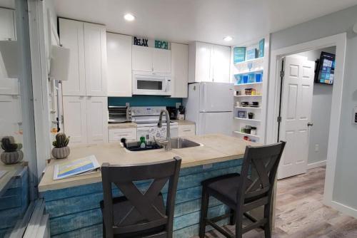 a kitchen with white cabinets and a sink and two chairs at Las Casitas on Magnolia Beach - Casita B in Port Lavaca