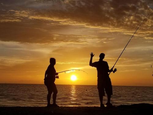 two people fishing on the beach at sunset at Las Casitas on Magnolia Beach - Casita B in Port Lavaca