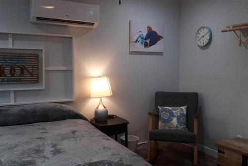 a bedroom with a bed and a chair and a clock at Las Casitas on Magnolia Beach - Casita B in Port Lavaca