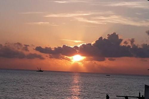 a sunset over the ocean with a boat in the water at Las Casitas on Magnolia Beach - Casita B in Port Lavaca