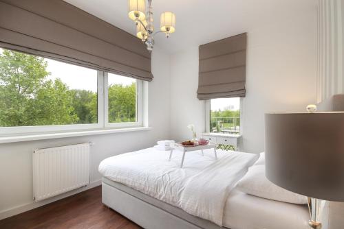 um quarto branco com uma cama e 2 janelas em Apartament Rataje Park Poznań - Parking - Widok - 24h check in em Poznań