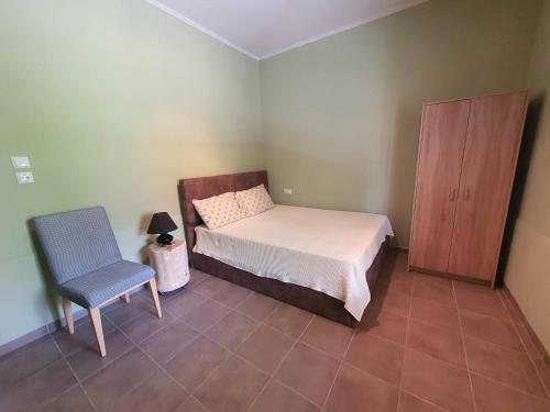 a bedroom with a bed and a chair and a cabinet at Lotaki the friendly house in Limenaria