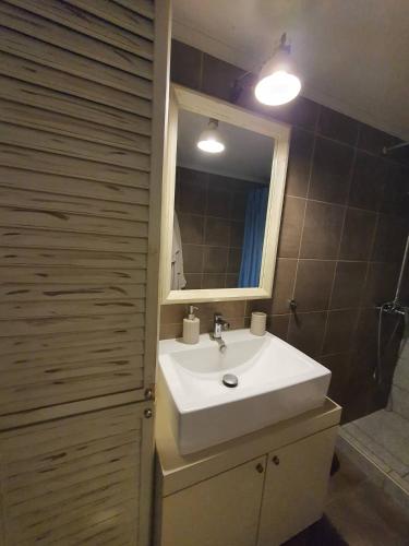 a bathroom with a white sink and a mirror at Lotaki the friendly house in Limenaria