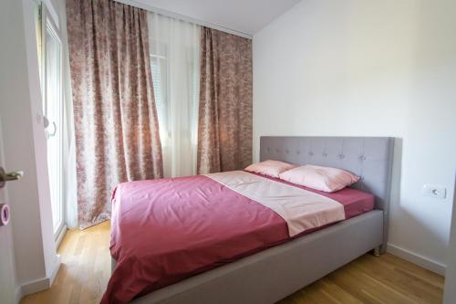 1 dormitorio con cama con sábanas rosas y ventana en SUN apartment, en Podgorica