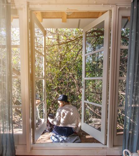 a man sitting in a window of a house at Blue House In The Woods- Amirim in Amirim