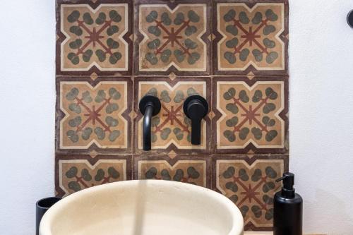 a bathroom with a tile wall with a sink at Othila Home in Noto