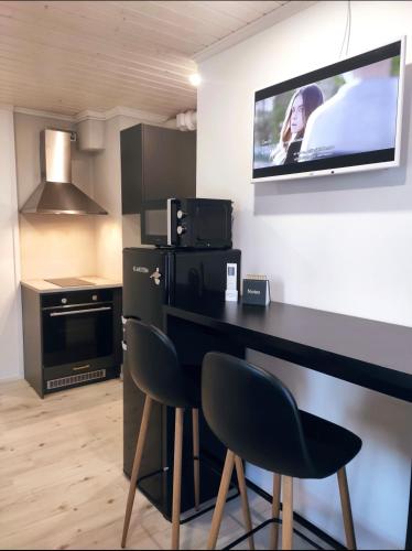 een keuken met een bureau met 2 stoelen en een tv aan de muur bij Upea moderni pieni yksiö rauhallisella sijainnilla - itsepalvelukirjautuminen - SELF CHECK-IN in Vaasa