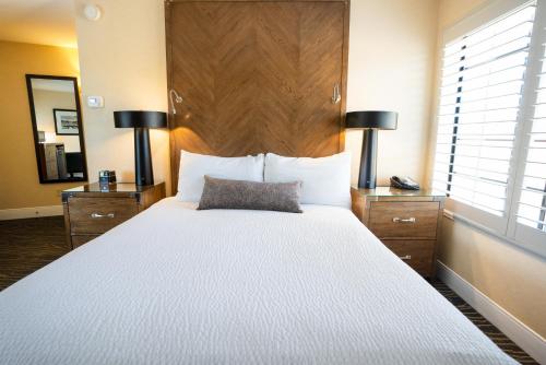 a bedroom with a large white bed with a wooden headboard at Best Western Plus Stevenson Manor in Calistoga