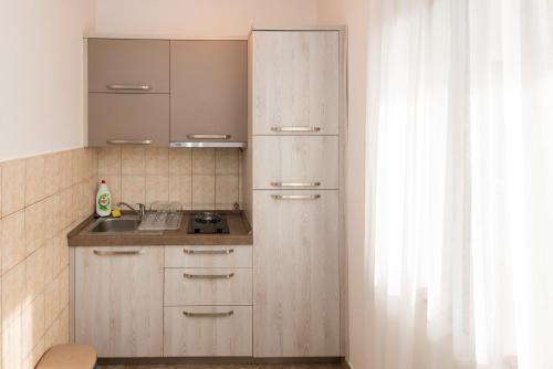 a kitchen with wooden cabinets and a sink next to a window at Apartments Kiki in Kotor