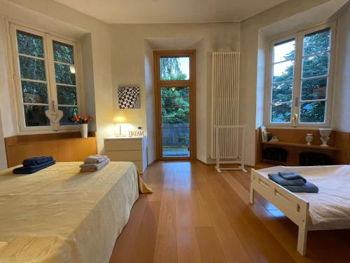 a bedroom with two beds and two windows at Lake Como Villa Ines Apartment in Faggeto Lario 