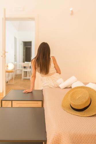 a young girl standing on a bed with a hat on it at Le Dimore di Puglia - Palazzo Ladogana in Monopoli