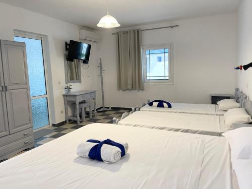 a hotel room with three beds and a television at Koala Place in Vasiliki