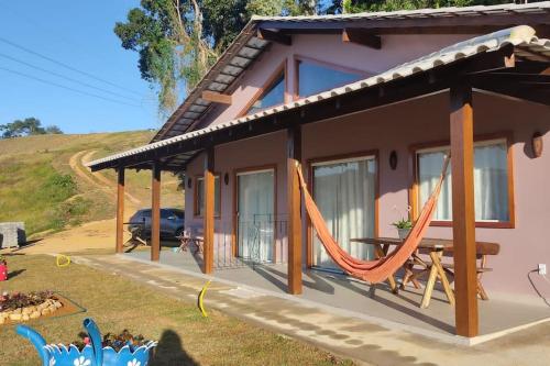 una casa con una hamaca delante en Vale do Sossego Chalés en Domingos Martins