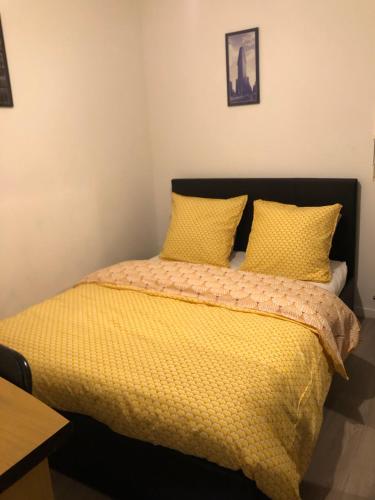 une chambre avec un lit avec des draps et des oreillers jaunes dans l'établissement Chambre Simple privée Saint Priest, à Saint-Priest