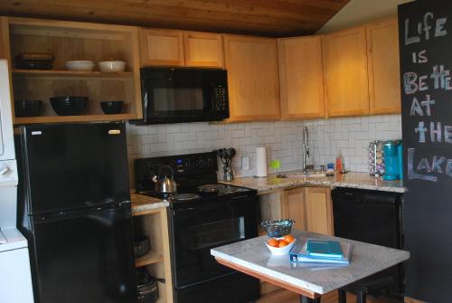 uma cozinha com armários de madeira e um frigorífico preto em Lake Front cottage em Little Elm