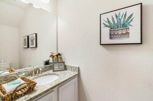 La salle de bains est pourvue d'un lavabo et d'une plante en pot sur le mur. dans l'établissement Pensacola Paradise, à Pensacola