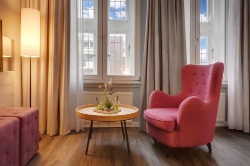 a living room with a pink chair and a table at Radisson Blu Hotel Bremen in Bremen