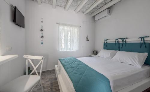 a bedroom with a bed and a tv and a chair at Santa Marina Milos in Mytakas