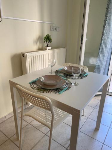 a white table with two plates and glasses on it at Kozani elegant. Διαμέρισμα στο κέντρο της κοζάνης in Kozani