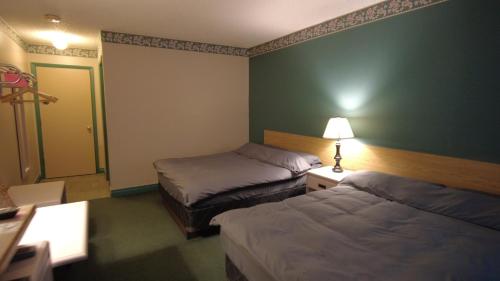 a hotel room with two beds and a lamp at Sundre Motor Inn in Sundre