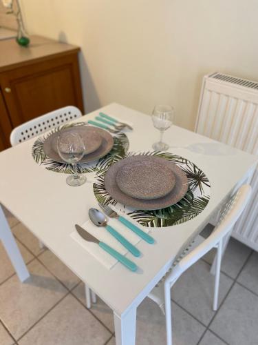 a white table with plates and silverware on it at Kozani elegant. Διαμέρισμα στο κέντρο της κοζάνης in Kozani