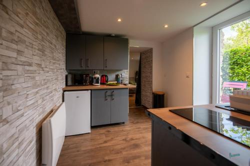 una cucina con armadietti bianchi e un muro di mattoni di Naturel : Studio calme et agréable a Les Bordes