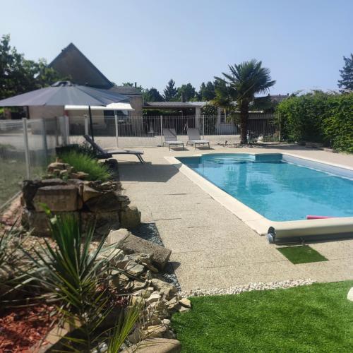 une piscine dans une cour avec un parasol dans l'établissement Naturel : Studio calme et agréable, à Les Bordes