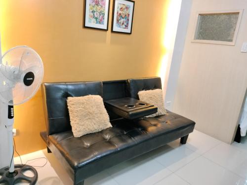 a black leather couch in a living room with a fan at Vangie's Place at SEA RESIDENCES in Manila