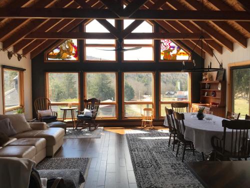 a living room with a table and chairs and windows at The Blue House On The Hill Catskills—Views in Claryville